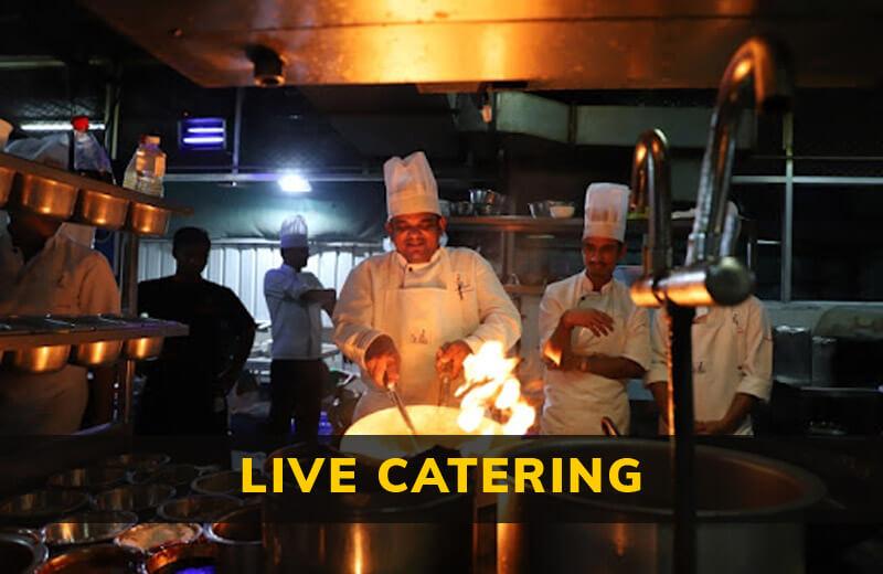 A chef preparing dishes at a live catering event with a variety of food items visible